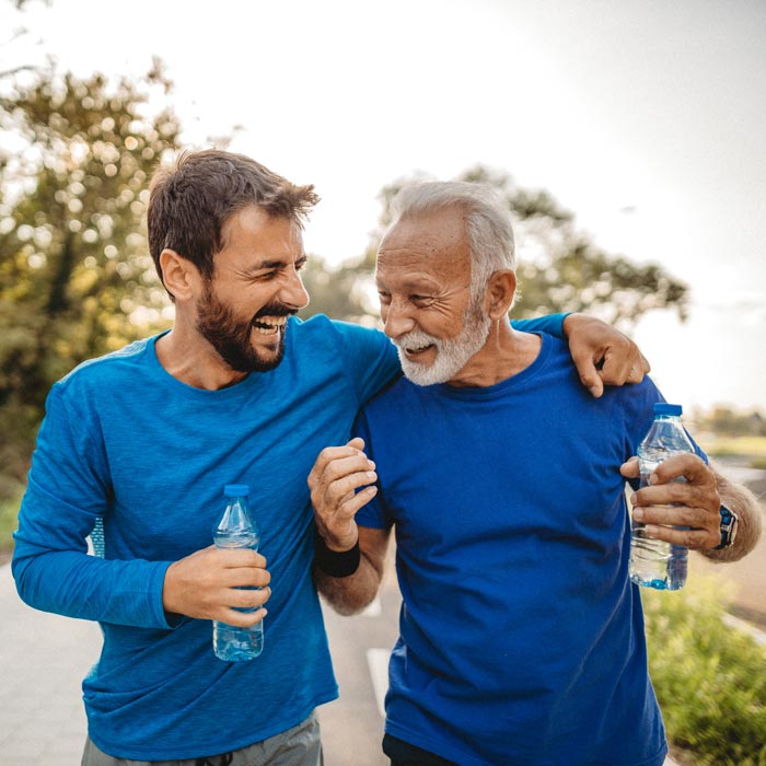 A young and older man drinking water and jogging at a park in Maryland