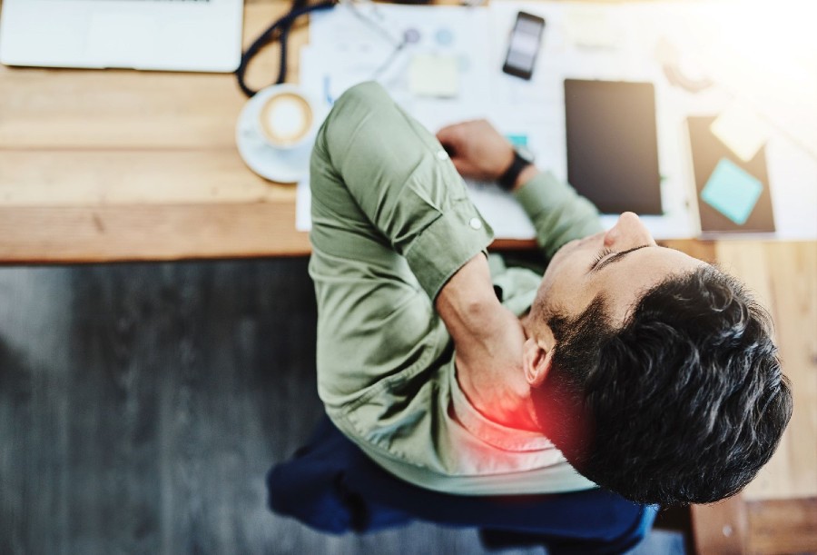 A man working in his Maryland home office grabs his neck to relive pain