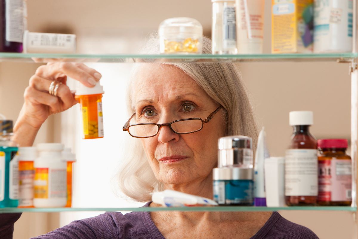 A woman looking at her medicine shelf for alternate pain medications in Greater Maryland.