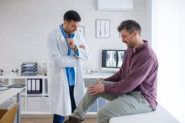 Man explaining his knee pain to his doctor