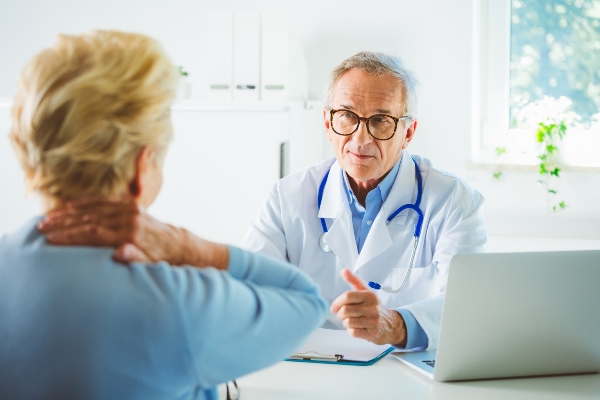 Woman with neck pain in consultation with doctor
