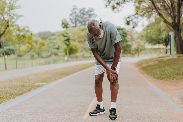 Senior man struggling with knee pain in park