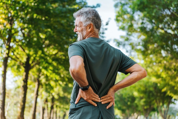 Senior man with back pain walking in park