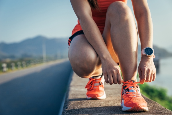 Woman tying shoe as she prepares to run