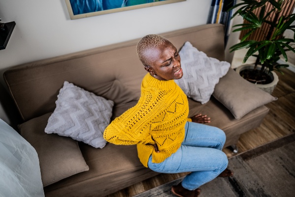 Woman with back pain sitting on couch