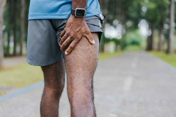 Man holding back of upper thigh in pain