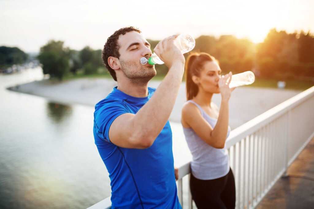 man and woman drinking water to stay hydrated