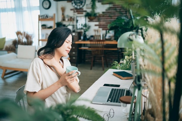 A woman holds her neck to try and find pain relief while she is working from her home in Maryland.