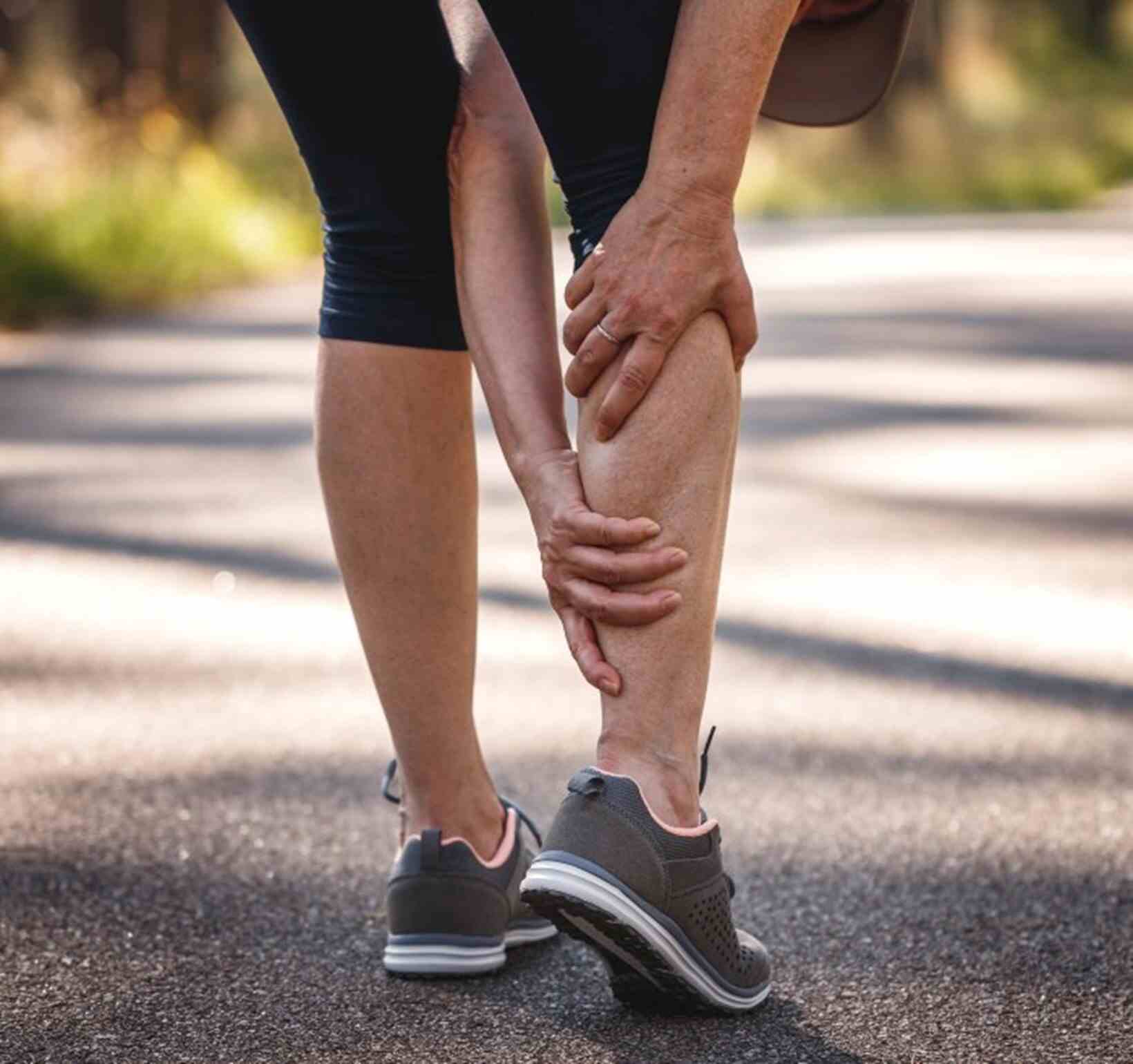 Man experiencing severe calf pain while jogging at a park in Maryland